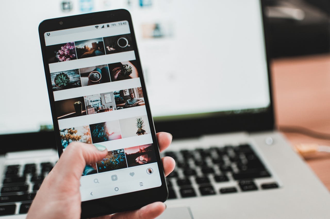 Mastering the First Impression: Your intriguing post title goes here A person uses a smartphone to browse social media in front of a laptop, emphasizing modern technology and lifestyle.